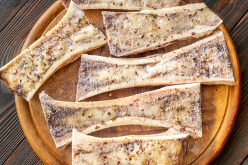 Rustic roasted marrow bones rest on warm wooden board, savory richness revealed