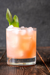Guava rum punch cocktail with pineapple garnish on moody tropical evening backdrop