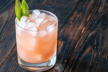 Guava rum punch cocktail with pineapple garnish on moody tropical evening backdrop