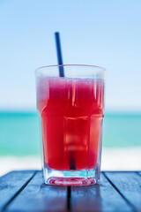 Fresh juice of watermelon on a wooden table in the background of the sea and beach. Shallow depth of field