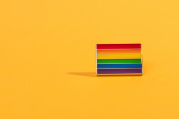 LGBT Badge accessory on a rainbow background.