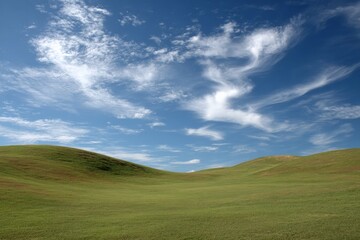 Fototapeta premium Rolling green hills under a bright blue sky with scattered clouds in a serene landscape