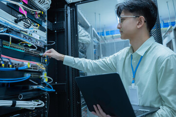 Computer engineer is setting up network in server room,Systems Maintenance Technician,Male engineer working in server room at modern data center