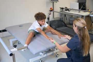Multiracial boy engages in flexibility exercises on therapy table