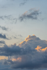 beautiful gray-blue cumulus clouds with orange tops illuminated by the sun, the mood of summer relaxation and travel