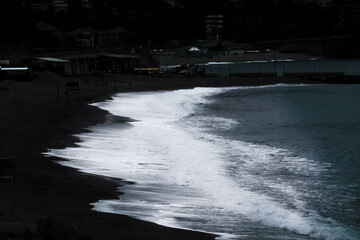 sea ​​waves on the beach with dark colors, from the white of the sea to the black of the beach