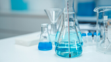 Glass labware with blue liquid in a modern science laboratory, representing chemical research, technology, and scientific experiments in a controlled environment.