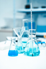 Glass labware with blue liquid in a modern science laboratory, representing chemical research, technology, and scientific experiments in a controlled environment.