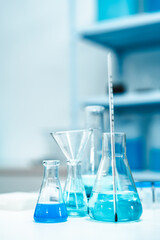 Glass labware with blue liquid in a modern science laboratory, representing chemical research, technology, and scientific experiments in a controlled environment.