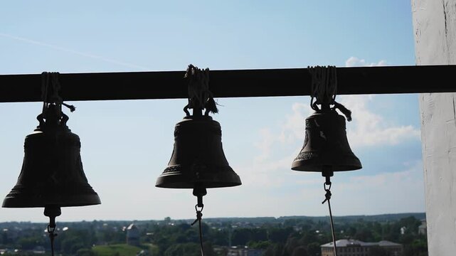 The bells are hanging on a rope in the chapel tower against the sky. Close-up shooting