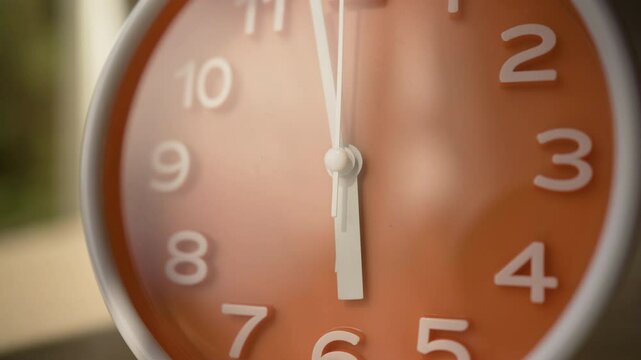Scheduling Concept. Orange clock showing 18.00 or 6.00 o'clock standing in the morning on Wooden Surface.