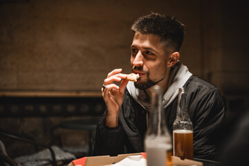 Man enjoying food and drink in a cozy setting during the evening with friends nearby