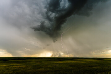 Dark clouds develop as lightning strikes overhead, creating a dramatic view filled with shadow,...