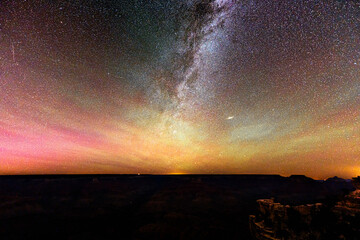 Milky Way and northern lights glow spectacularly over the Grand Canyon, creating an epic, colorful...