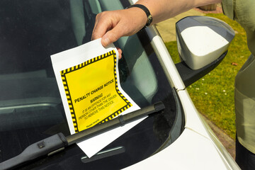 Unwelcome moment woman driver finds Penalty Charge Notice (parking ticket. Image conveys the...