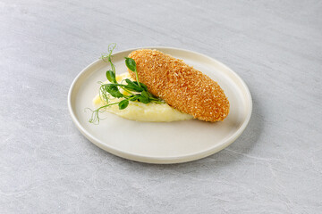 Chicken Kiev Cutlet with Mashed Potatoes and Pea Shoots on Beige Plate