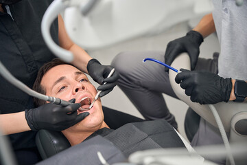 Dentist drilling male client tooth to remove caries and clean fissures