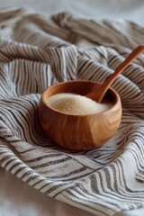 Wooden bowl of sugar on a striped kitchen cloth, rustic scene