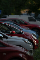 A beautiful line of various cars parked in a lush green environment, showcasing a range of different colors and models