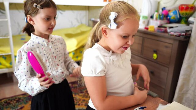 Two little girls friends getting ready for school in bedroom. Kid braids sisters hair. Children wear school uniforms. Morning routine. Doing homework, home lessons. Education back to school concept