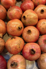 Fresh ripe pomegranates displayed on a market stall in the afternoon sunlight