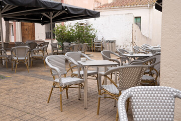 Empty outdoor cafe terrace with wicker chairs and tables in courtyard setting