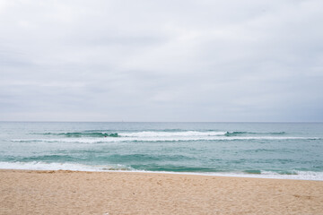 Tranquil seascape with gentle waves and cloudy sky at sandy beach