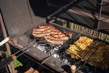 Grilled sausages and chicken on barbecue grill outdoors on a sunny day