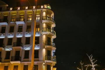 Illuminated nighttime urban building with decorated balconies and dark sky