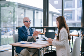 Senior manager explaining marketing strategy to young businesswoman during a meeting in a modern...