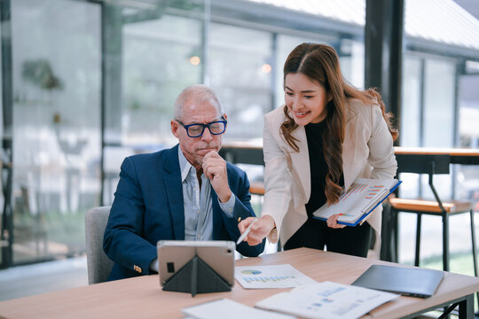Business partners working together on new company project analyzing financial charts and graphs using digital tablet and documents showing positive growth results in modern office