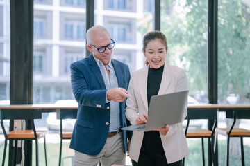 Senior manager engaging in a discussion about project details with a young businesswoman,...