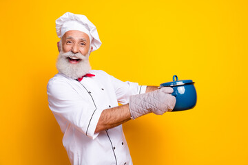 Happy senior chef holding a cooking pot, smiling with enthusiasm