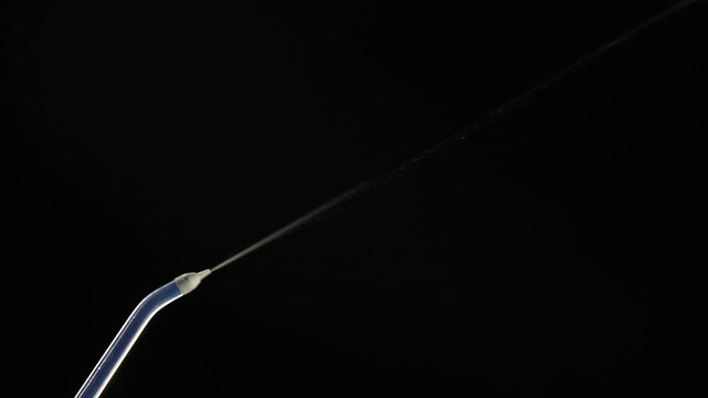 Portable oral irrigator on black background, close up. Dental teeth whitening, flosser bucal tooth cleaner, waterpulse, water thread for teeth. Stream of water from an irrigator nozzle