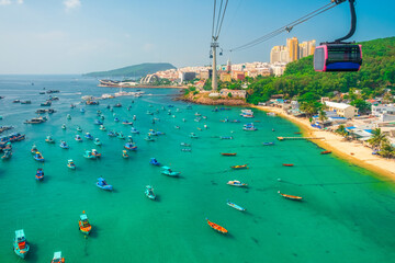 Aerial view of coastal fishermen village with fishing boats, turquoise sea and modern cable car gondola ride on Phu Quoc island, Vietnam. Modern Hon Thom cable car cabin. Tourism infrastructure © samael334