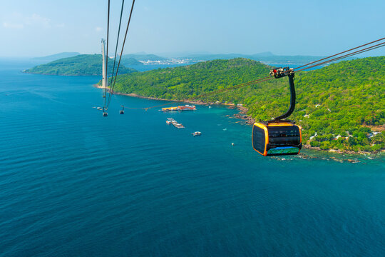 Aerial view of cable car gondola gliding over turquoise sea and green tropical island. Longest Hon Thom cable car ride in the world on Phu Quoc island, Vietnam. Modern tourism technology - Powered by Adobe