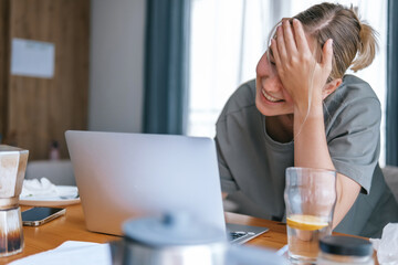  Gen Z woman working from home at cozy kitchen table with laptop and phone. Digital nomad lifestyle, mindfulness, remote work, balance, mental calm and modern freelancing