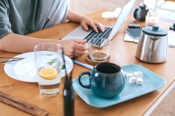  Gen Z woman working from home at cozy kitchen table with laptop and phone. Digital nomad lifestyle, mindfulness, remote work, balance, mental calm and modern freelancing