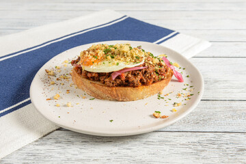 Savoring a Delicious Open-Faced Sandwich Topped With Savory Meat, Fried Egg, and Fresh Ingredients at a Cozy Brunch Spot