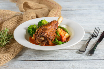 Savory Slow-Cooked Lamb Shank Served With Vibrant Vegetables on a Rustic Wooden Table