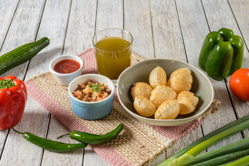 Delicious Street Food Platter Featuring Puffed Puris and Tangy Chutneys on a Wooden Table With Vibrant Vegetables