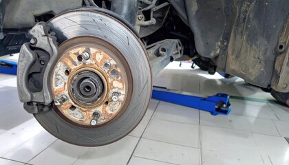 Close-up of car brake disc and caliper during vehicle maintenance process