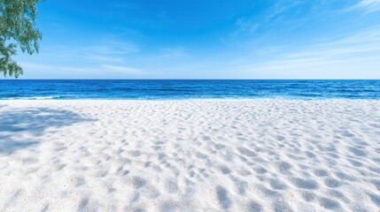 Obraz premium Pristine white sand beach stretches to azure ocean under a vibrant blue sky. Lush tropical foliage casts a gentle shadow