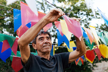 Elderly man preparing decorations for a traditional Festa Junina celebration