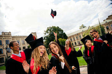 Joyful young graduates throw hats in celebration on a sunny day outdoors
