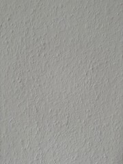 Close-up texture of a white plastered wall with subtle bumps and uneven surface, ideal for background or design mockups.