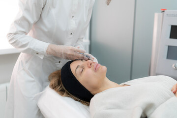 Naklejka premium A nurse carefully injects a serum into a patient's face