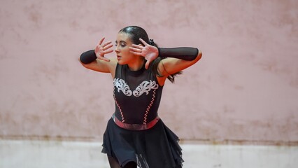 Young woman competing in a roller skating championship wearing a black and silver costume