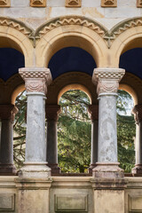 Obraz premium Detail of porticoed entrance gallery at Derio Cemetery, Spain, featuring marble columns, Romanesque arches and natural background