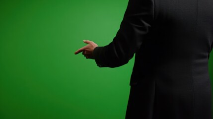 A man in a suit pointing to the left on a green screen background.